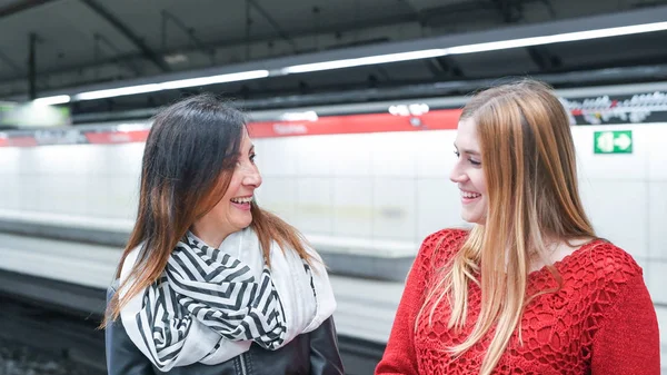 Pareja de amigas sonriendo y hablando en el metro stati — Foto de Stock