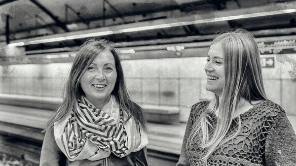 Pareja de amigas sonriendo y hablando en el metro stati — Foto de Stock