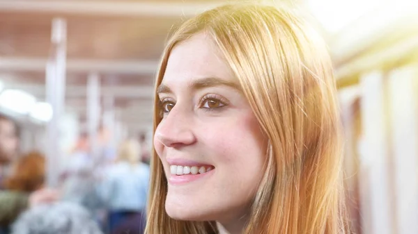 Happy blonde woman in a subway train.