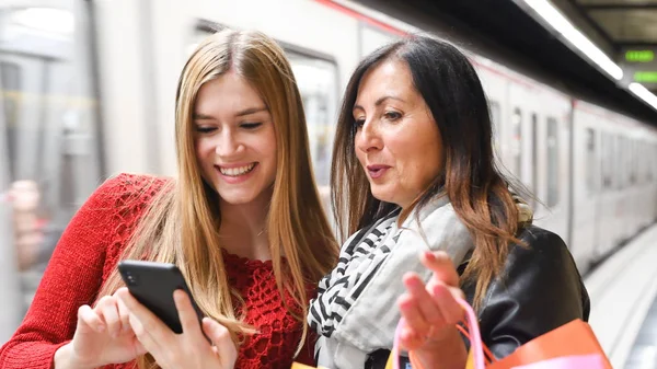 Un par de amigas sonriendo felices mirando al smartphone — Foto de Stock