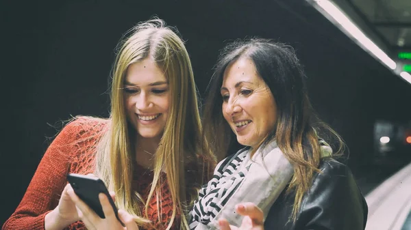 Un par de amigas sonriendo felices mirando al smartphone — Foto de Stock