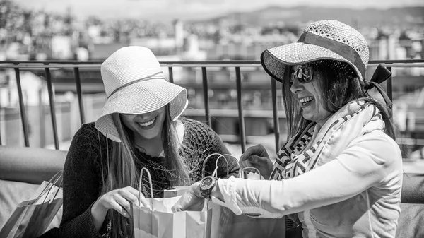 Un par de mujeres jóvenes en una azotea mirando dentro de bolsas de regalo — Foto de Stock