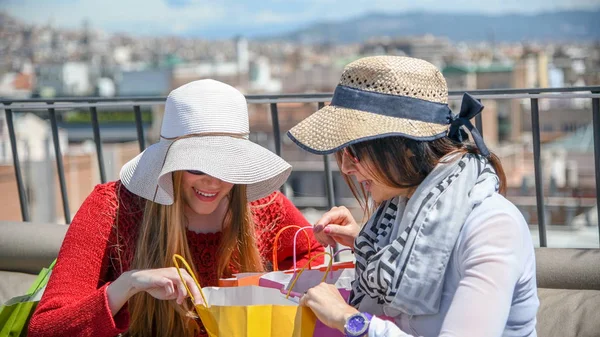 Friends enjoying city view while opening gift bags — Stock Photo, Image