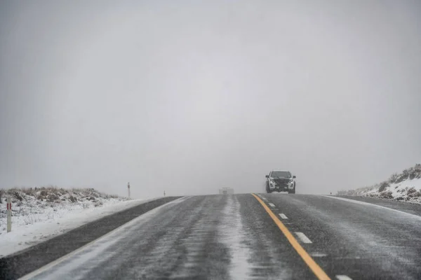 Снежная дорога зимой с приближающейся машиной — стоковое фото