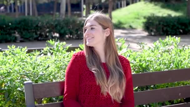 Πλάνα Από Όμορφη Νεαρή Γυναίκα Κάθεται Στον Πάγκο Στο Πάρκο — Αρχείο Βίντεο