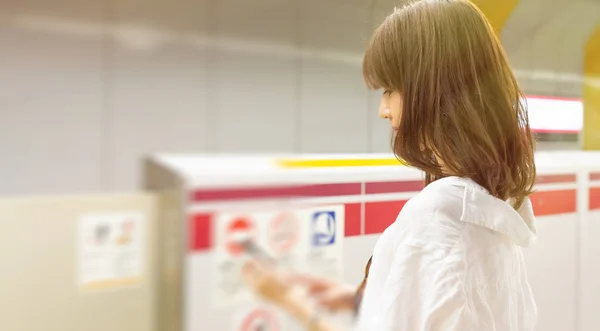 Fiatal ázsiai nő, a metró, vár egy vonat szöveg — Stock Fotó