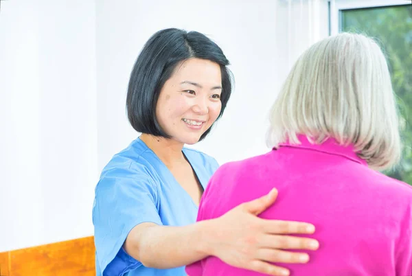 Aged senior woman assisted by asian nurse — Stock Photo, Image