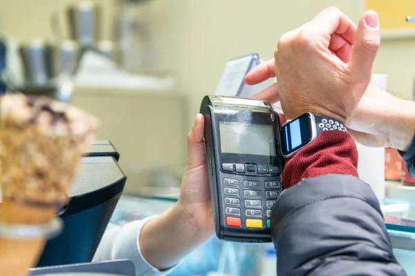 Un homme main tenant et utilisant la montre intelligente payer pour la crème glacée — Photo