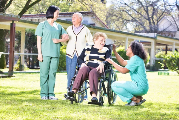 高齢者シニア人とマルチ民族の看護師の話と笑みを浮かべてガーデン グループ — ストック写真