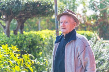 Bahçesinde çalışan, şapkalı, arka ışıklandırmalı mutlu bir emekli adam..