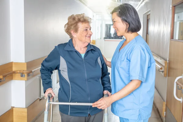 Asyalı Kadın Doktor Olgun Yaşlı Kadını Walker Rahatlatıyor Hastane Koridorunda — Stok fotoğraf