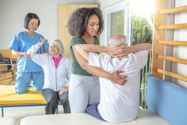Paar verpleegkundigen helpen actieve Senior paar bij rehab Gym. Reti — Stockfoto