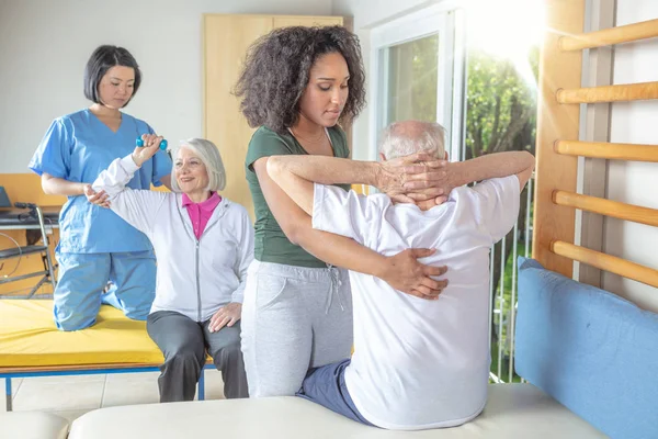 Rehabilitasyon salonunda aktif yaşlı çifte yardım ediyor. Reti — Stok fotoğraf