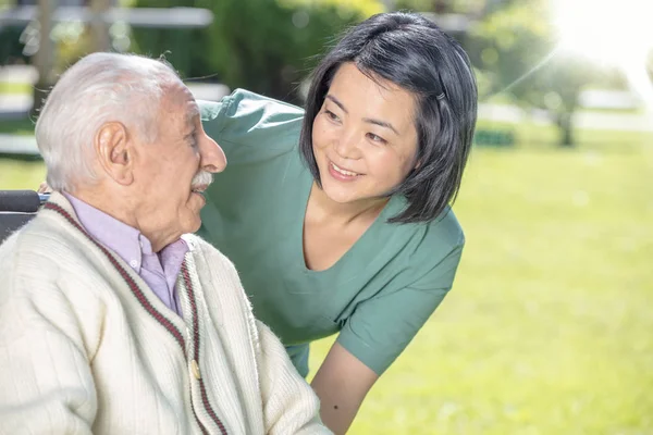 病院の庭で成熟した老人と遊んで笑顔アジアの女性医師 退職者コミュニティ構想 — ストック写真