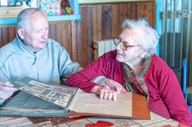 Evde eski fotoğraf albümlerine bakan yaşlı çift.