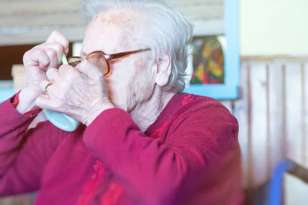 Oudere vrouw in de rolstoel die thuis koffie drinkt — Stockfoto