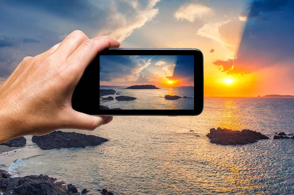 Mão feminina com smartphone tirando uma foto do belo pôr do sol — Fotografia de Stock