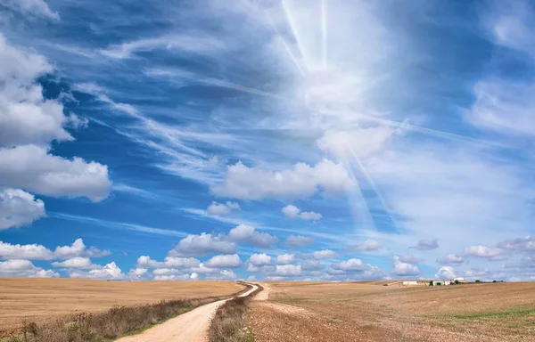 Bela estrada rural ventosa contra o céu azul com nuvens. H — Fotografia de Stock