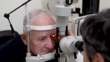 Doktorun yaşlı bir hastanın göz temasını kontrol ettiği görüntüler.