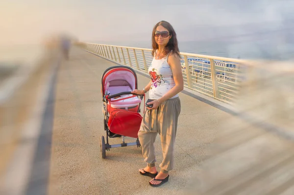 Mujer feliz al aire libre con su hijo recién nacido dentro de la cuna. Mo. — Foto de Stock