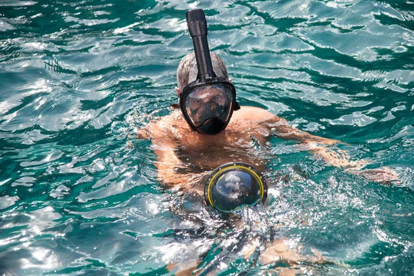 Man with mask and underwater photographic equipment going for ex