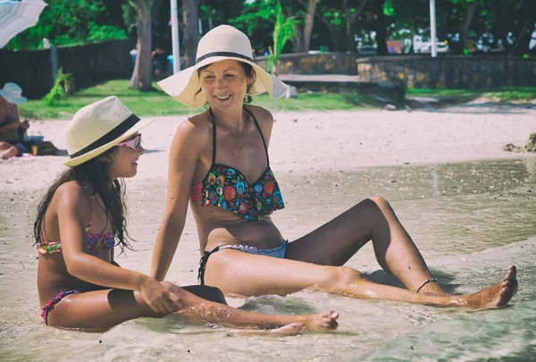 Madre e hija hablando en una hermosa playa, sentadas en el —  Fotos de Stock