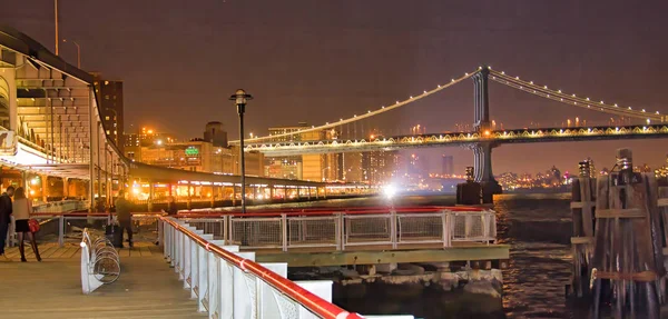 Pier 17 i New York City på natten med stadssilhuett utsikt — Stockfoto