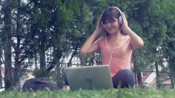 女子高生がノートパソコンを使って草の上で — ストック動画