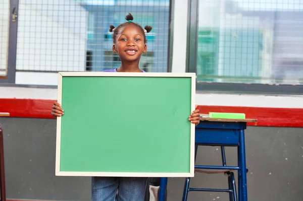Young african girl at school holding chalkboard — Stock Photo, Image