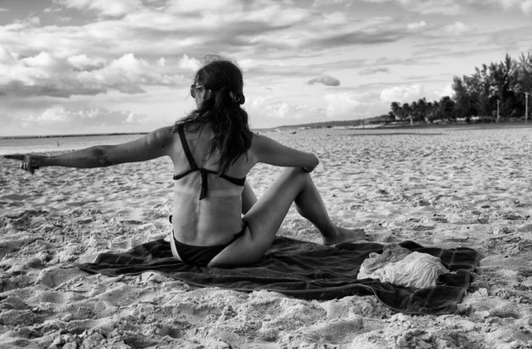Жінка вказує пальцем десь сидить на пляжі на заході сонця — стокове фото