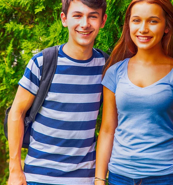 Пара підлітків посміхається стоячи в парку — стокове фото