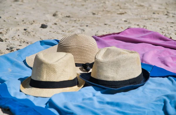 Strohhüte und bunte Handtücher am Strand — Stockfoto