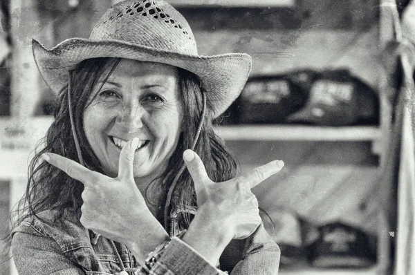 Western uśmiechnięta kobieta nosi słomkowy kapelusz symulujący strzały pistoletu dowcip — Zdjęcie stockowe