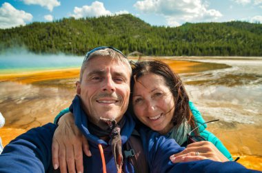 Büyük Prizmatik Bahar Gayzeri, Yellowstone Ulusal Parkı 'nın arka planında selfie çeken mutlu çift..