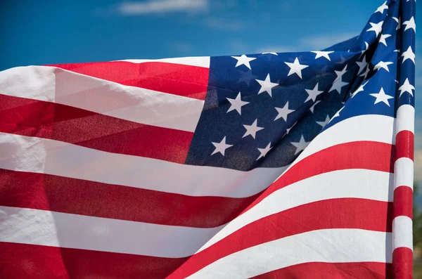 Mavi gökyüzü arka plan üzerinde Amerikan bayrağı sallayarak — Stok fotoğraf