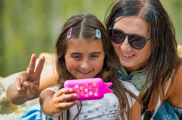 Mujer sonriente con su hija fingiendo hacer una selfie con —  Fotos de Stock