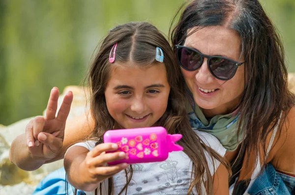 Mosolygó nő a lányával úgy tesz, mintha szelfit csinálna — Stock Fotó