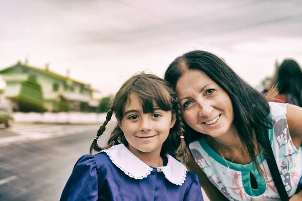 Young girl with her mother leaving home for her first day of ele — Stock Photo, Image