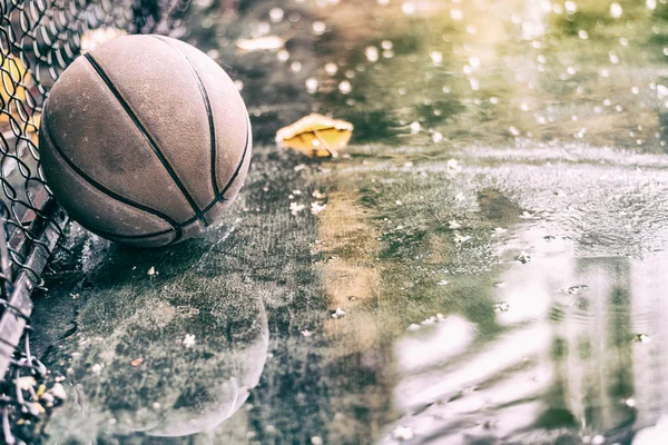 Övergivna basket på en utomhus fält med regn och pölar — Stockfoto