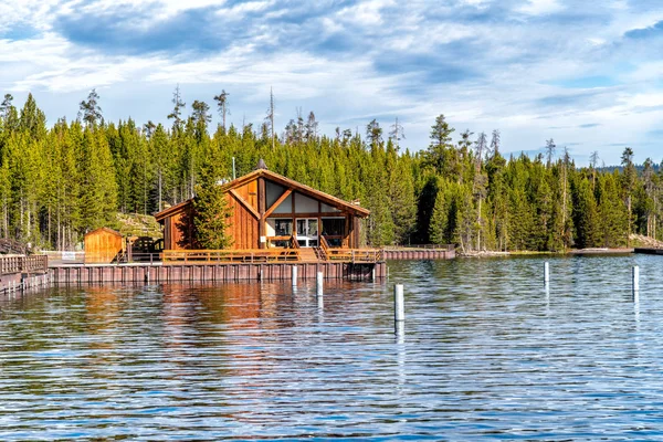 Casa de madeira em Yellowstone Lake com árvores reflexos de água — Fotografia de Stock