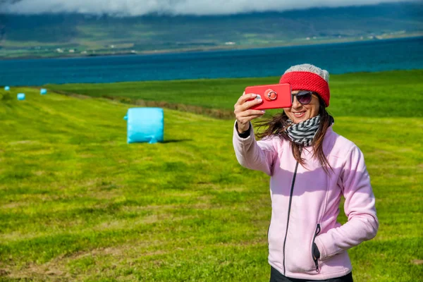Kobieta robi selfie z czerwonym smartfonem w Islandii landscpae sce — Zdjęcie stockowe