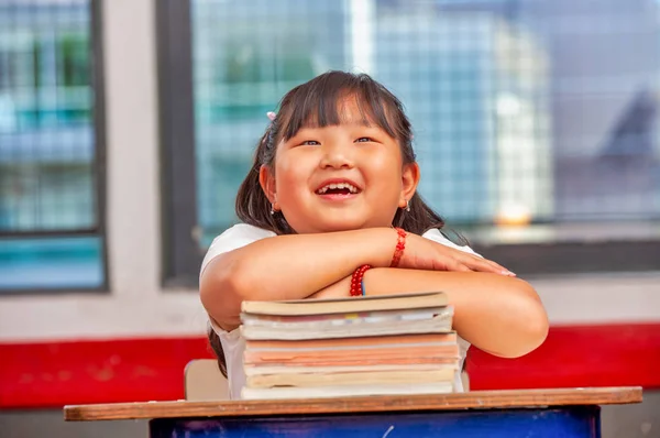 Menina asiática feliz com as mãos sobre os livros na escola — Fotografia de Stock