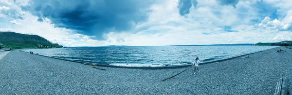 Barn som leker längs Yellowstone Lake Beach, panoramautsikt, USA. — Stockfoto