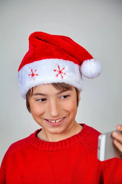 Glückliches Kind mit Weihnachtsmütze macht Selfie mit Smartphone — Stockfoto