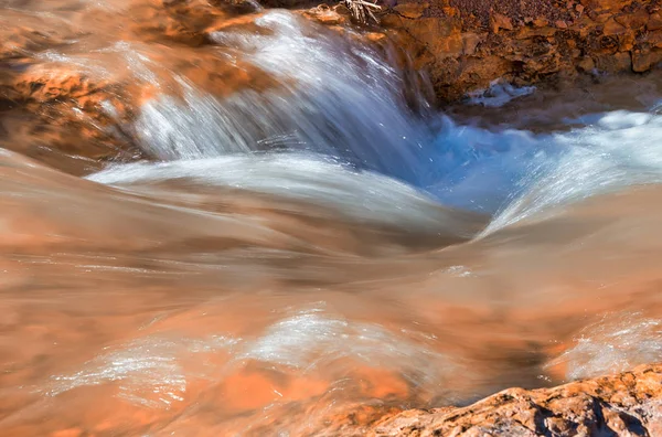 Verschwommener Blick auf fließendes Wasser gegen rote Felsen — Stockfoto