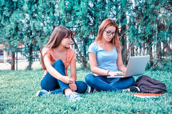 两个亚洲和高加索女孩在城市公园里用笔记本电脑 — 图库照片