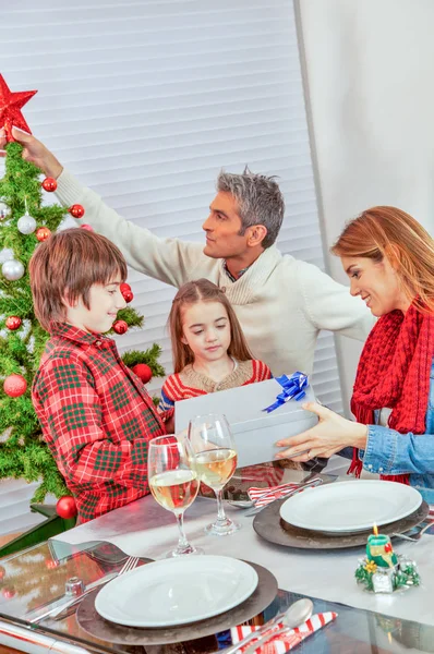 Happy family holding Christmas gift at home — Stock Photo, Image
