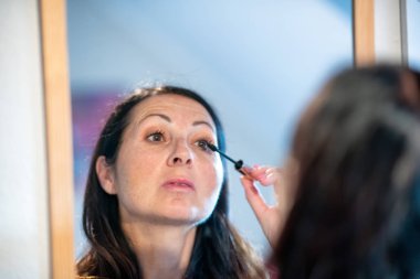 Aynanın önünde makyaj yaparken güzel bir kadın.