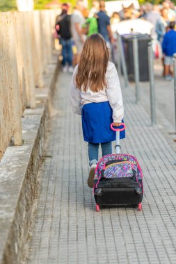 Trolle ile okula gelen genç kız öğrencinin geri görünümü