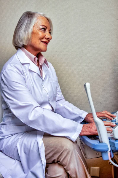 Ultrasound at hospital. Elderly female doctor confident at work — Stock Photo, Image